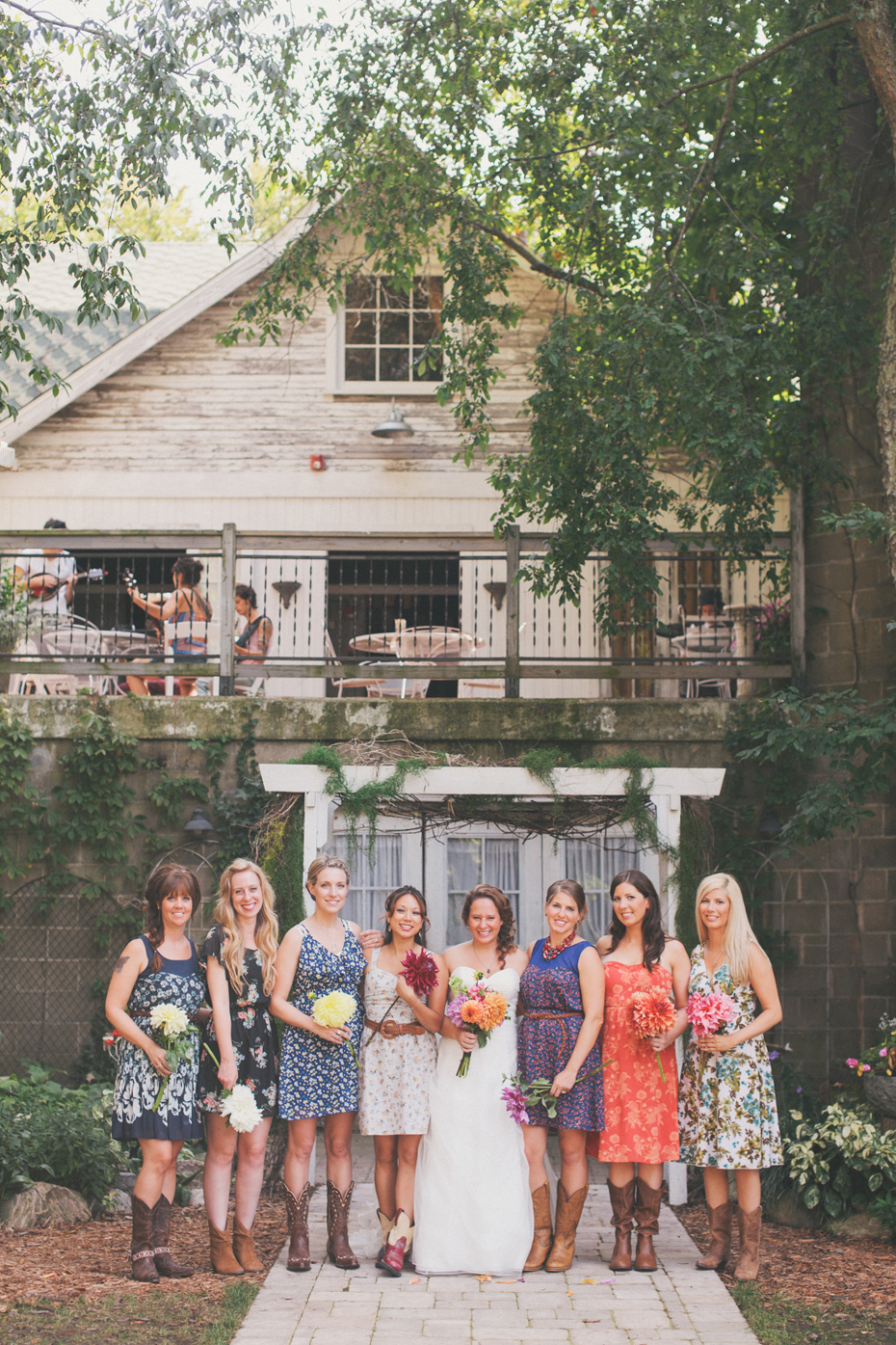 Bridesmaids in Floral Dresses and cowboy boots photographed by Ann Arbor Michigan wedding photographer Heather Jowett at the Blue Dress Barn in Benton Harbor.