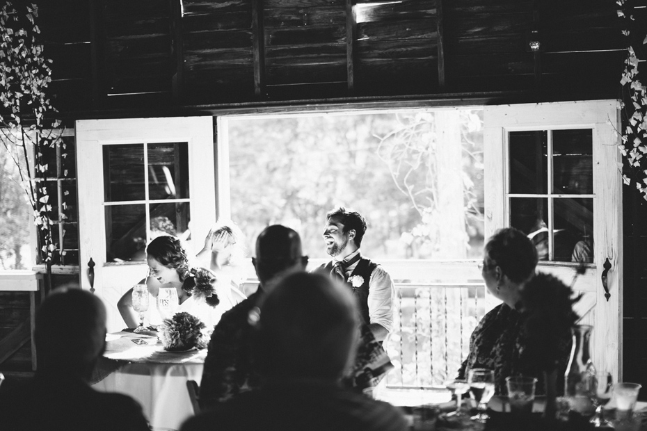 The bride and groom laugh at a toast at the Blue Dress Barn in Benton Harbor photographed by Ann Arbor Michigan wedding photographer Heather Jowett.
