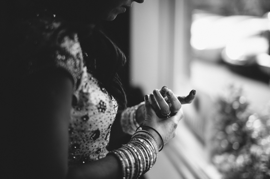 A bride puts on bangles and other jewelry for her hindu wedding reception, , by Ann Arbor wedding photographer Heather Jowett.