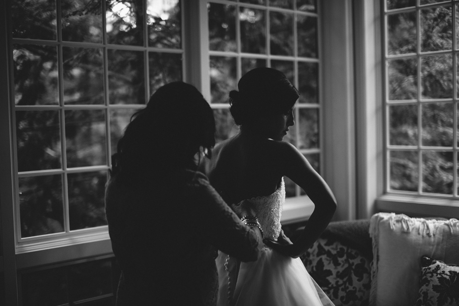 A bride's mother helps her get dress, by Ann Arbor wedding photographer Heather Jowett.