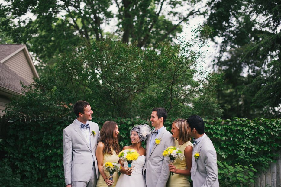A wedding party pose for a portrait in their suits with bowties and yellow bridesmaid dresses, by Ann Arbor wedding photographer Heather Jowett.