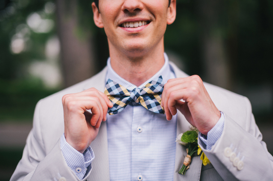 A groom straightens his bow tie.
