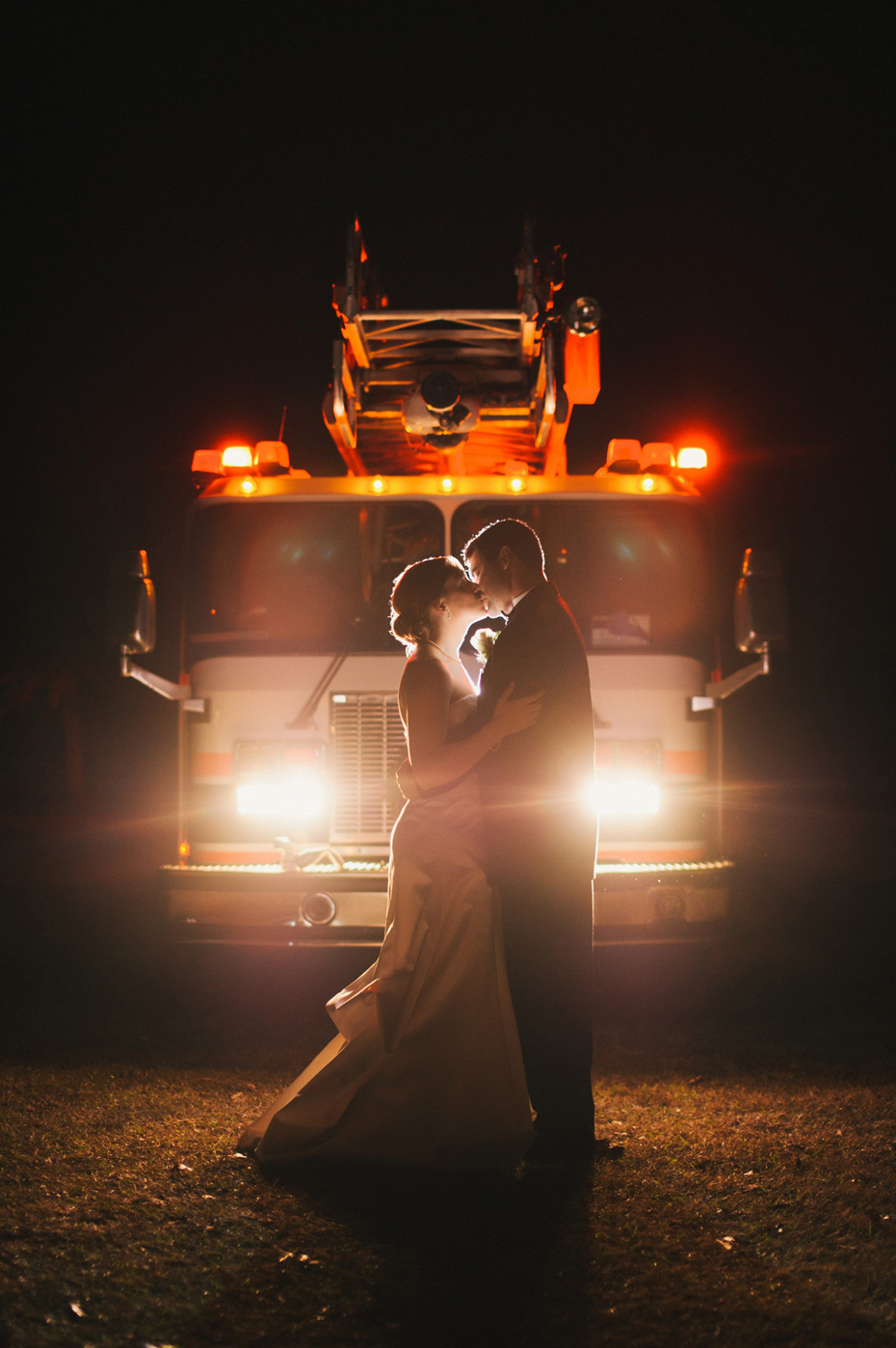 A bride and groom pose in front of a firetruck at their wedding reception at The Fountainview Mansion in Auburn Alabama, photographed by Ann Arbor Wedding Photographer Heather Jowett.