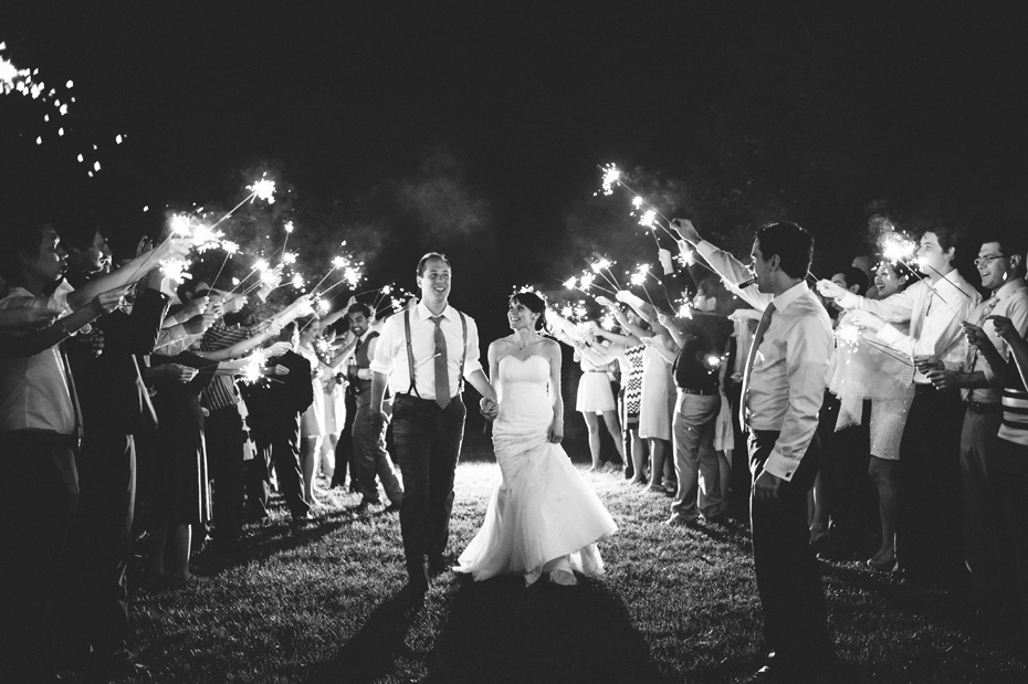 The bride and groom run through a sparkler exit at the end of their rustic vintage style backyard wedding in Bloomfield Hills, photographed by Michigan wedding photographer, Heather Jowett.