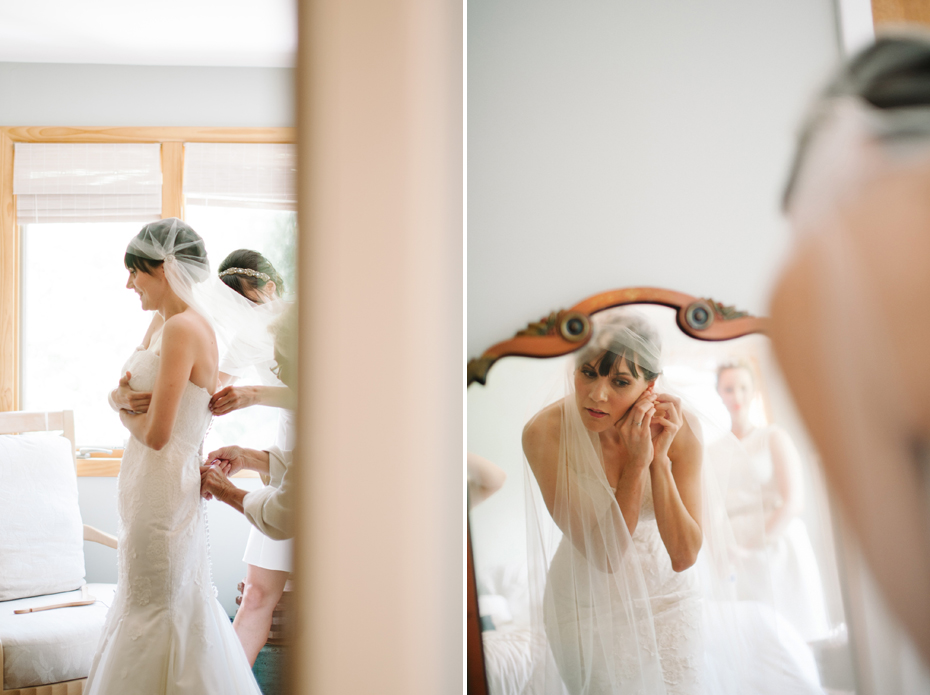 A bride is helped into her wedding dress by her bridesmaids and mother in this photograph by Ann Arbor Michigan wedding photographer, Heather Jowett.