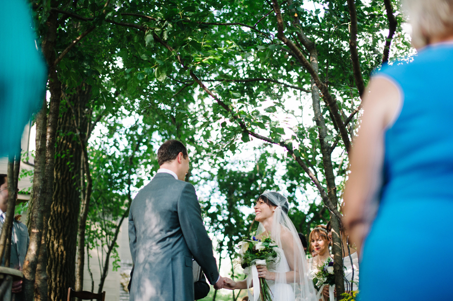 Bride and groom share a laugh during their backyard wedding ceremony by Detroit Michigan wedding photographer, Heather Jowett.