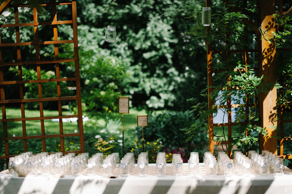 Mason jar escort cards at a backyard wedding reception by Ann Arbor Michigan wedding photographer, Heather Jowett.