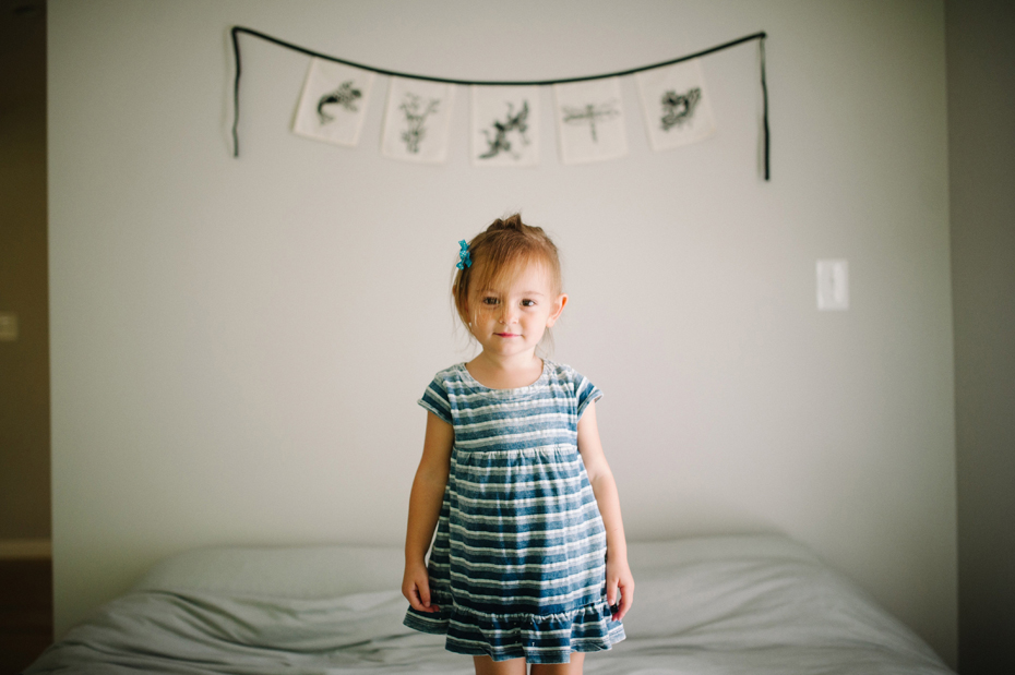 A 2 year old jumps on the bed during a documentary family portrait session in Ferndale photographed by Ann Arbor Wedding Photographer, Heather Jowett.