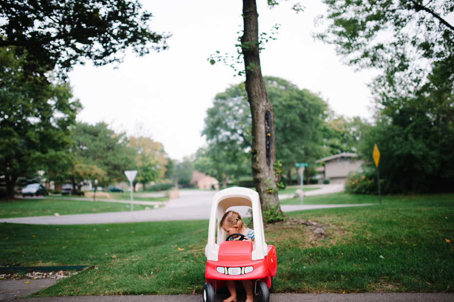 A two year old drives a toy car during a photojournalistic family portrait session in Ferndale photographed by Ann Arbor Wedding Photographer, Heather Jowett.