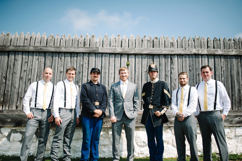 A groom and his groomsmen pose with guards at Fort Mackinac before his wedding at The Inn At Stonecliffe on Mackinac Island by Michigan Wedding Photographer Heather Jowett.