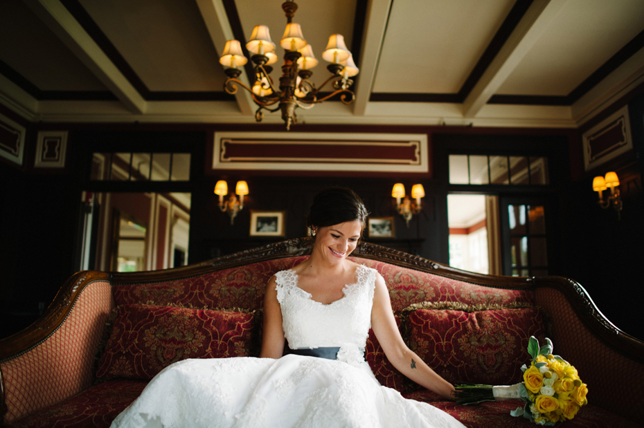 A bride poses on a vintage couch before her wedding at The Inn at Stonecliffe on Mackinac Island by Michigan Wedding Photographer Heather Jowett.