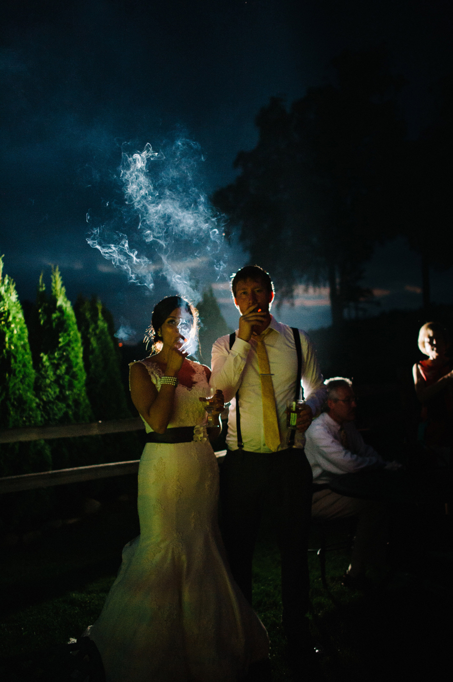 Bride and groom share a celebratory cigar during an outdoor wedding reception at The Inn at Stonecliffe on Mackinac Island by Ann Arbor Wedding Photographer Heather Jowett.
