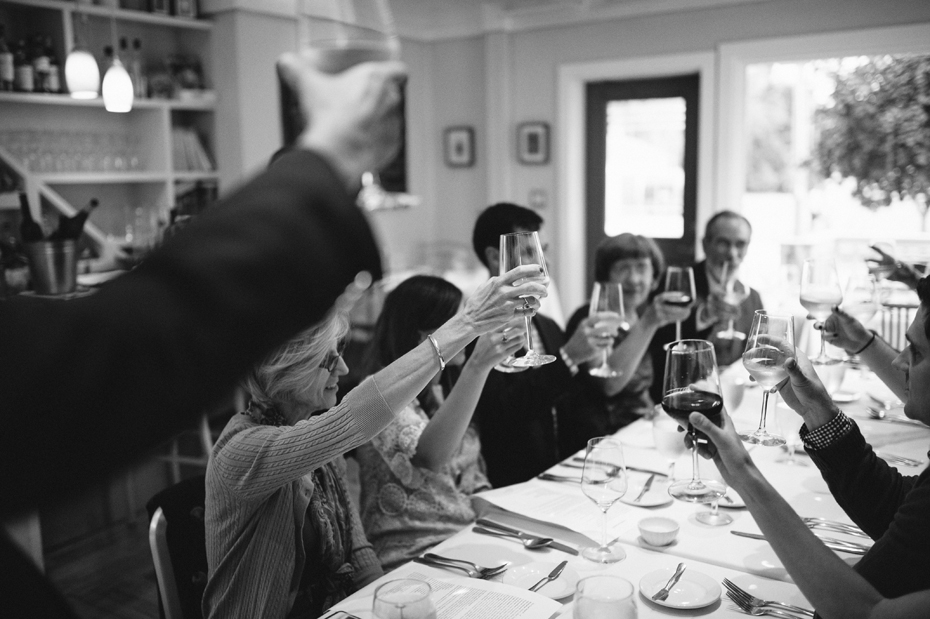 Family toasts the bride and groom to be at a rehearsal dinner at The Cooks House in Traverse City by Ann Arbor Michigan Wedding Photographer Heather Jowett.