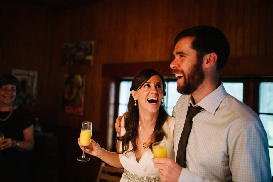 Bride and groom laugh during toasts after a Northern Michigan elopement by Ann Arbor Michigan Wedding Photographer Heather Jowett.