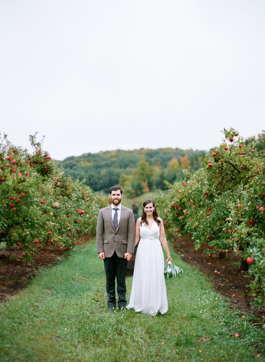 Bride and groom pose for portraits in a beautiful apple orchard after their elopement by Ann Arbor Michigan Wedding Photographer Heather Jowett.