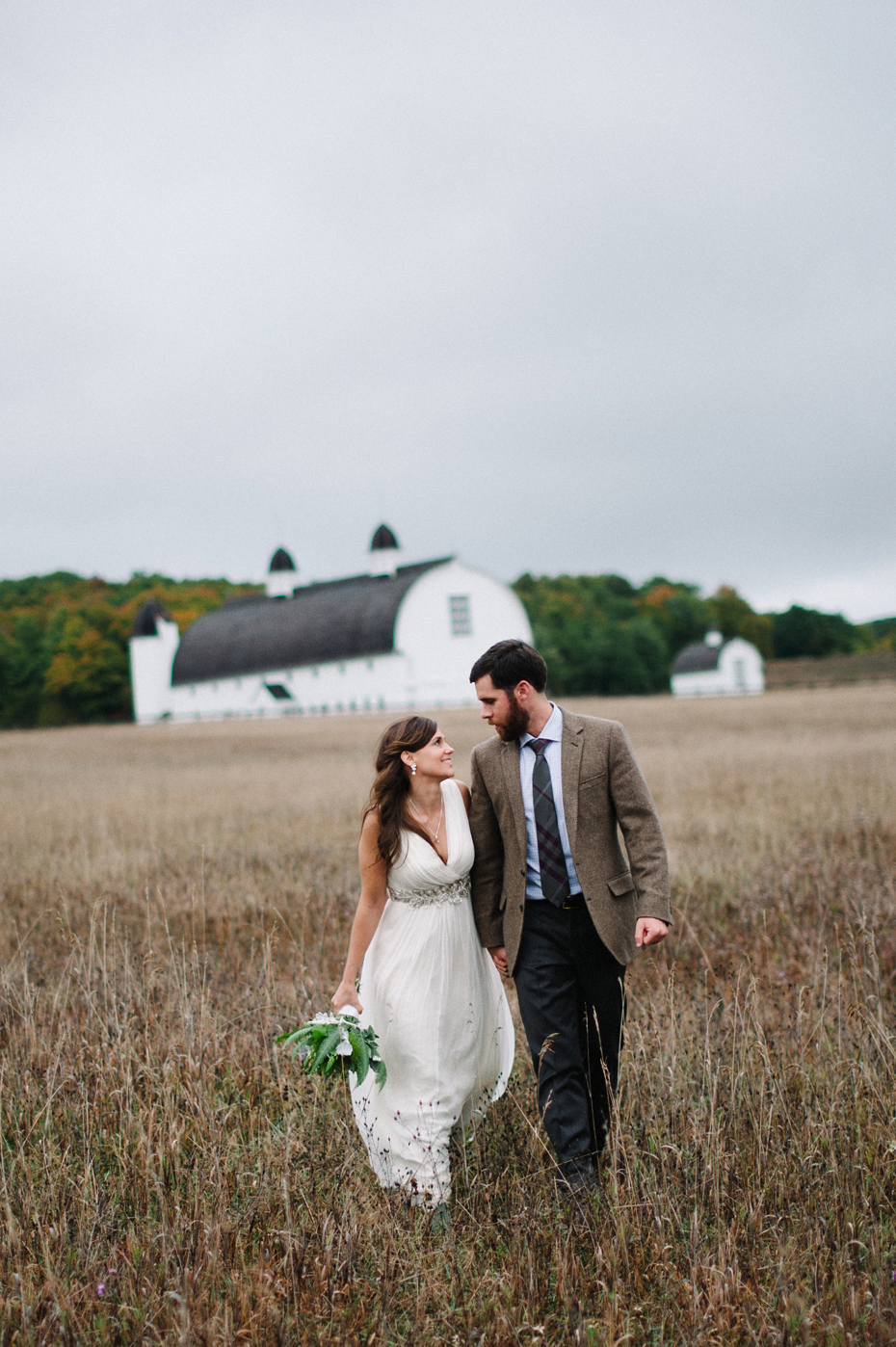 Bride and groom pose for portraits in a Northern Michigan field near Sleeping Bear Dunes after their elopement by Ann Arbor Michigan Wedding Photographer Heather Jowett.