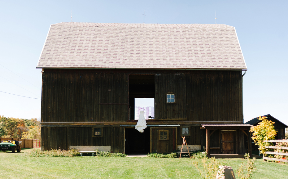 wedding dress hanging from the balcony of the barn at Misty Farms by photojournalistic Michigan wedding photographer Heather Jowett.