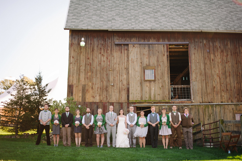 The wedding party poses by the barn at Misty Farms by photojournalistic Michigan wedding photographer Heather Jowett.
