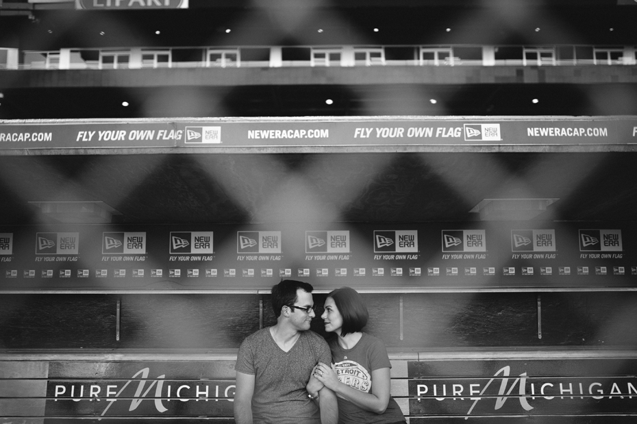 A couple poses for an engagement photo in the dugout at Comerica Park.