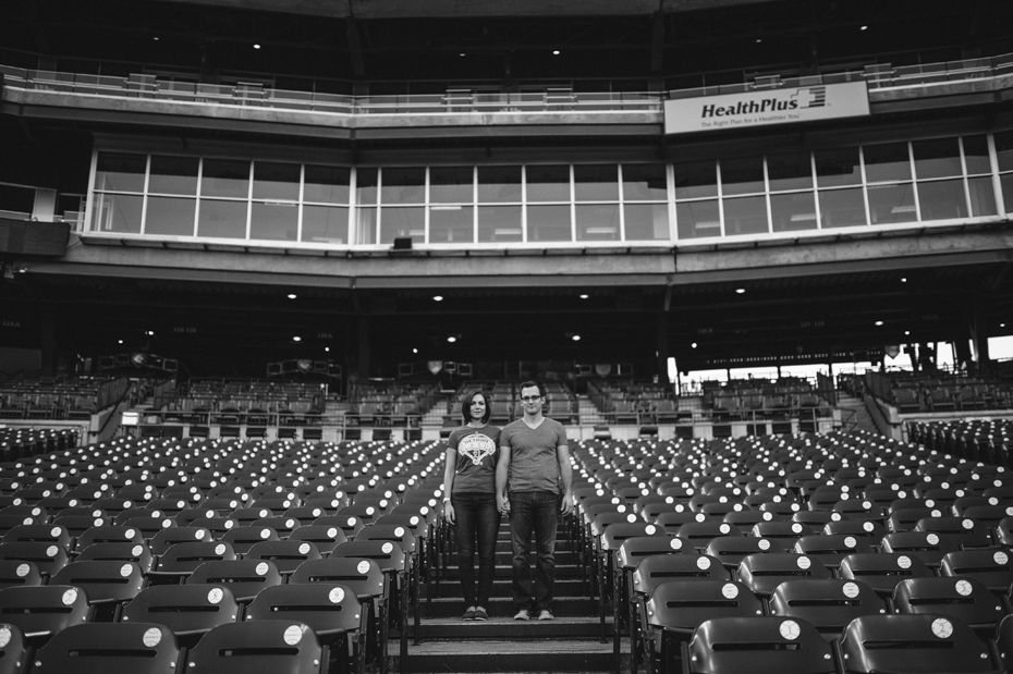 A couple posing in the empty seats during their engagement session at Comerica Park.