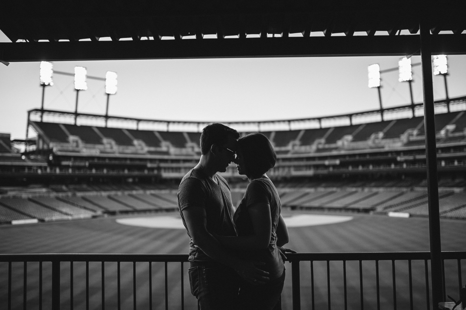 A couple posing with the empty stadium and field during their Tigers Baseball themed engagement session at Comerica Park.