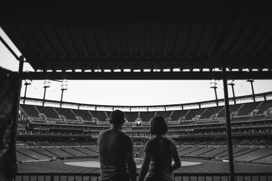 A couple posing with the empty stadium and field during their Tigers Baseball themed engagement session at Comerica Park.