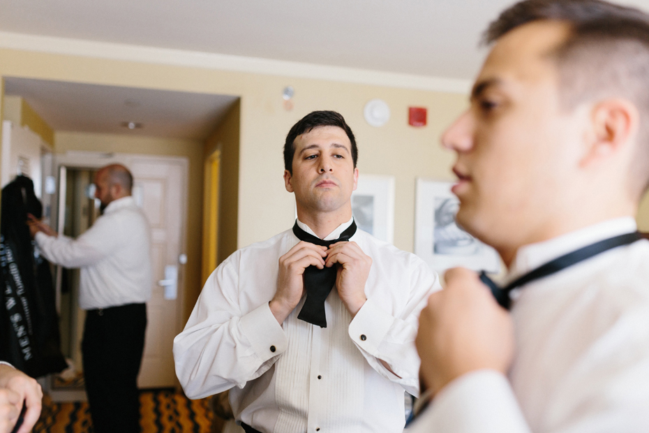 The groom ties his bow tie before his Greek Orthodox ceremony by Virginia Wedding Photographer, Heather Jowett.