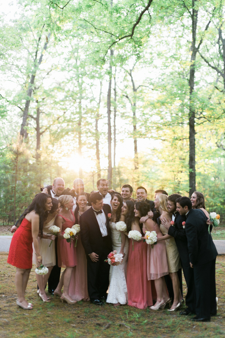 Bridesmaids in mismatched coral dresses and Groomsmen in tuxes and bow ties pose for portraits at the Noland Trail by Virginia Wedding Photographer, Heather Jowett.