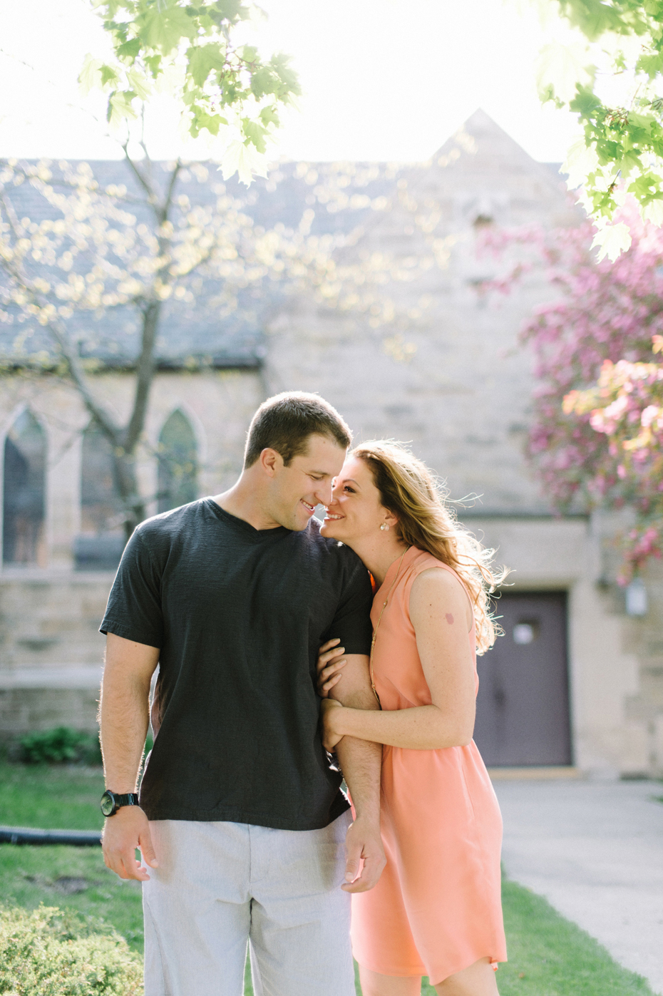 A couple poses for engagement photos near an old church by Michigan wedding photographer Heather Jowett