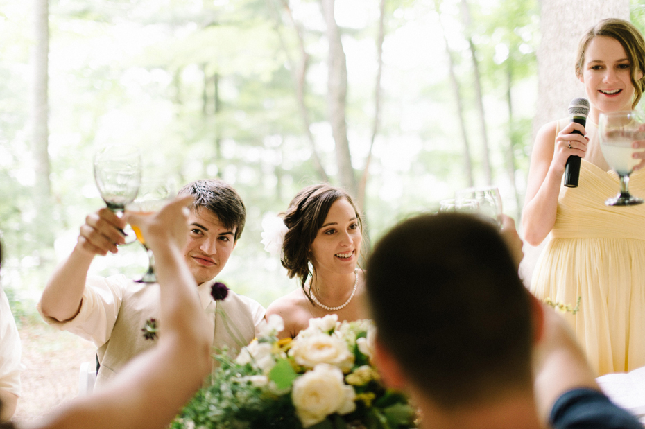 Bride and groom laughing toasting with their guests.