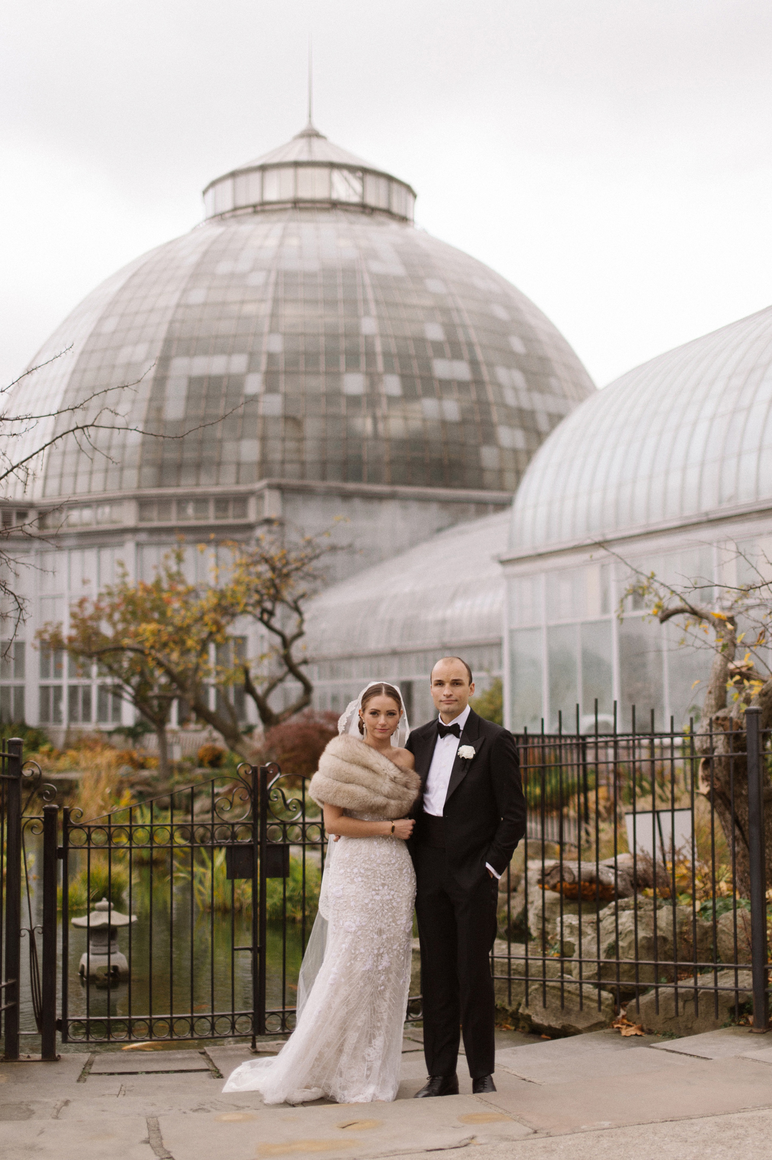 Bride and groom pose for wedding portraits by the Conservatory on Belle Isle in Detroit.