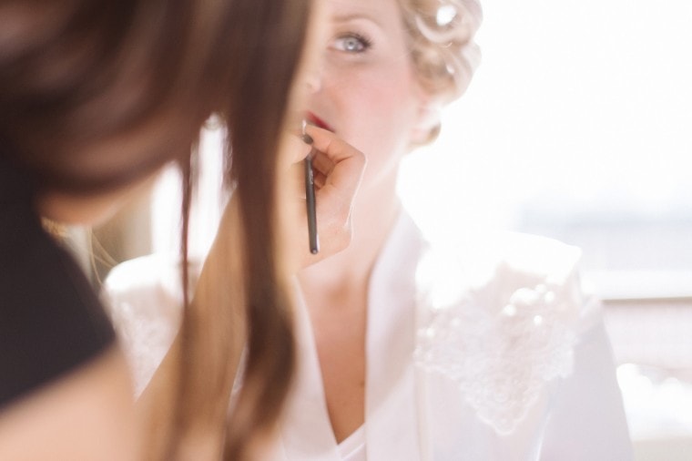 A bride puts on red lipstick at the Westin in Detroit.
