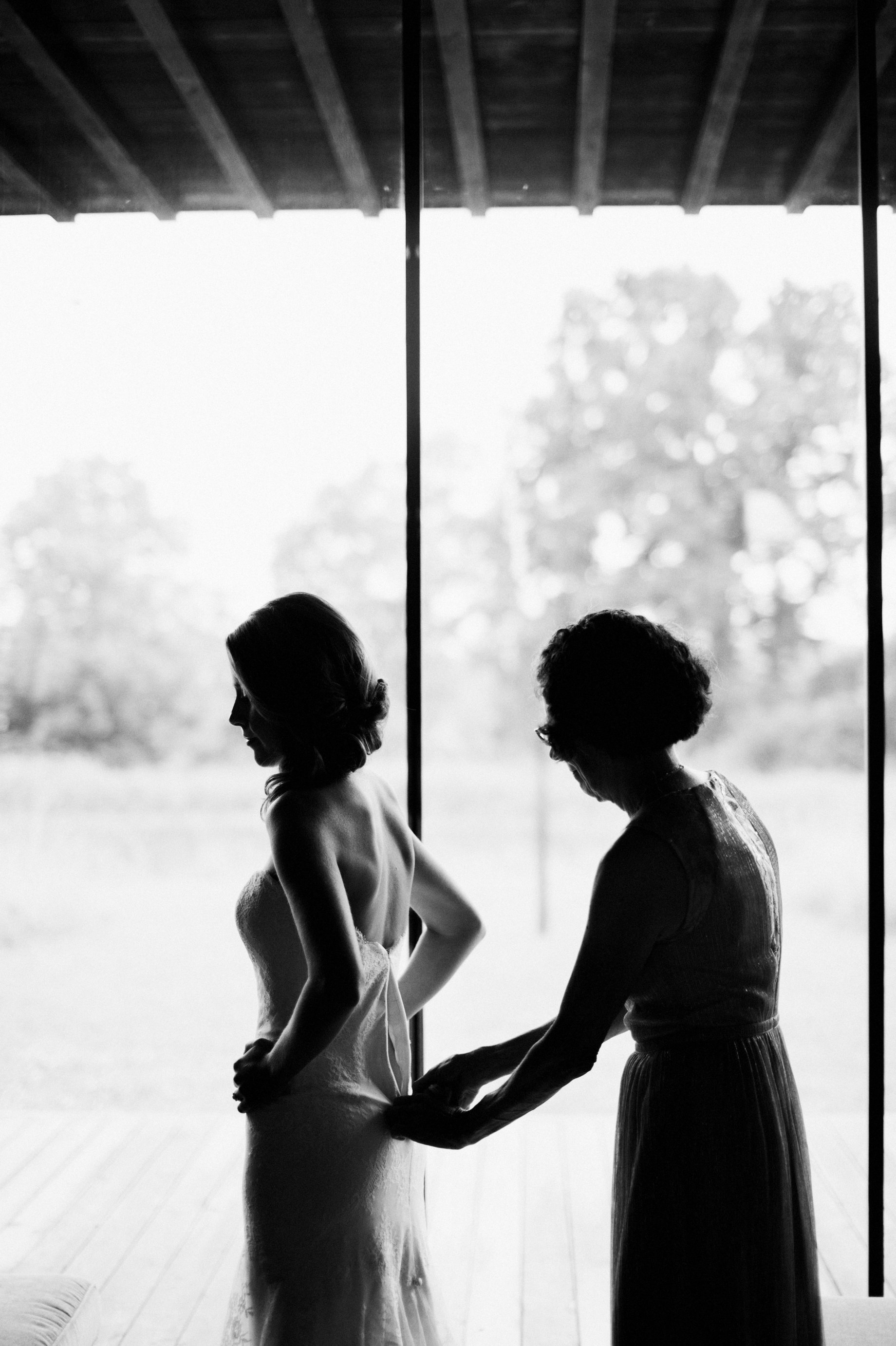 mother helping bride into her wedding dress