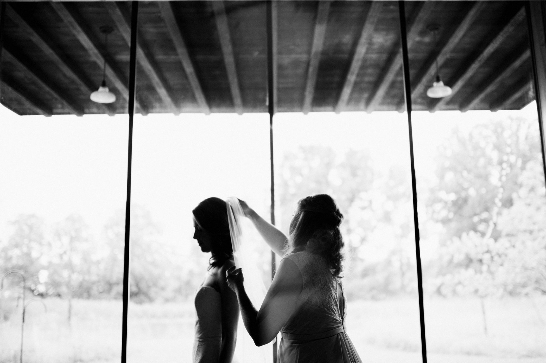 older sister of the bride placing her veil