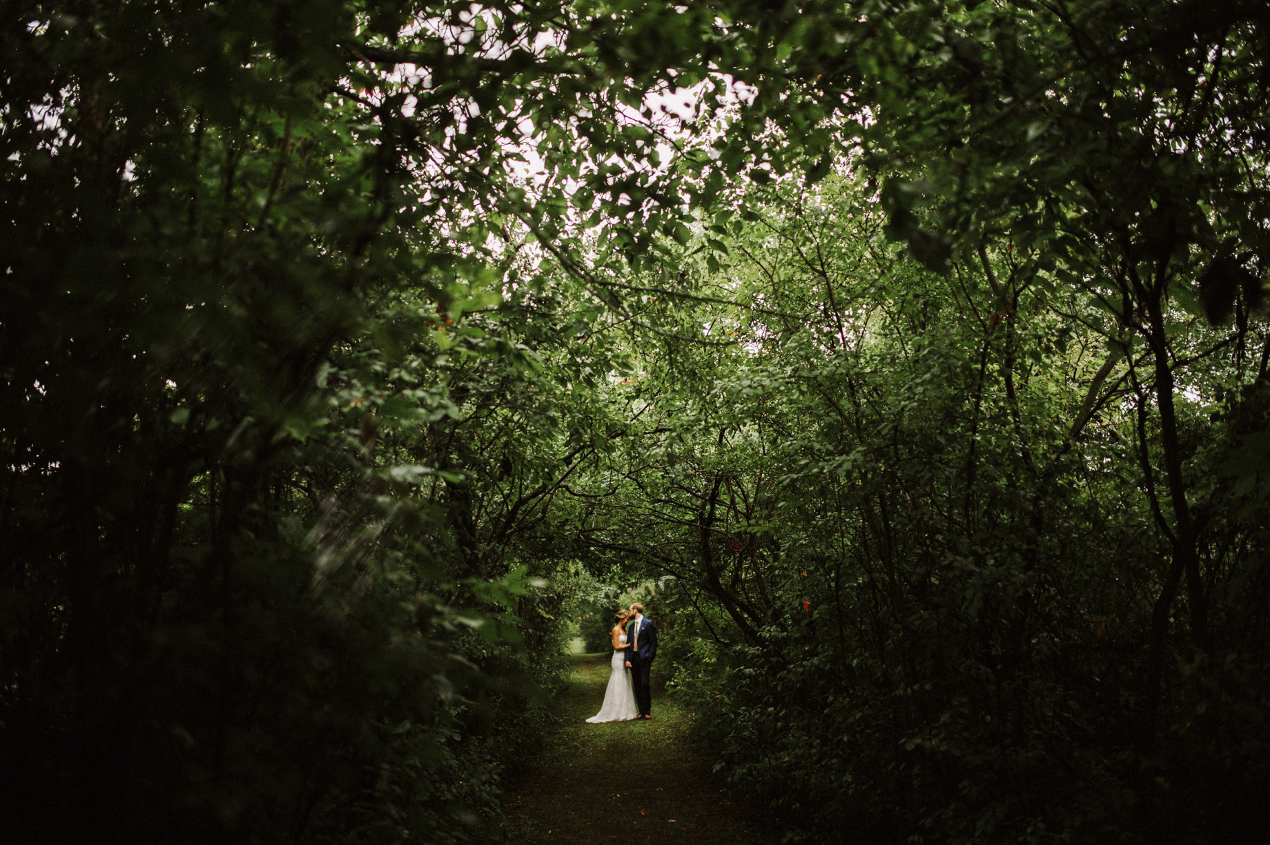 bride and groom on a trail in the woods