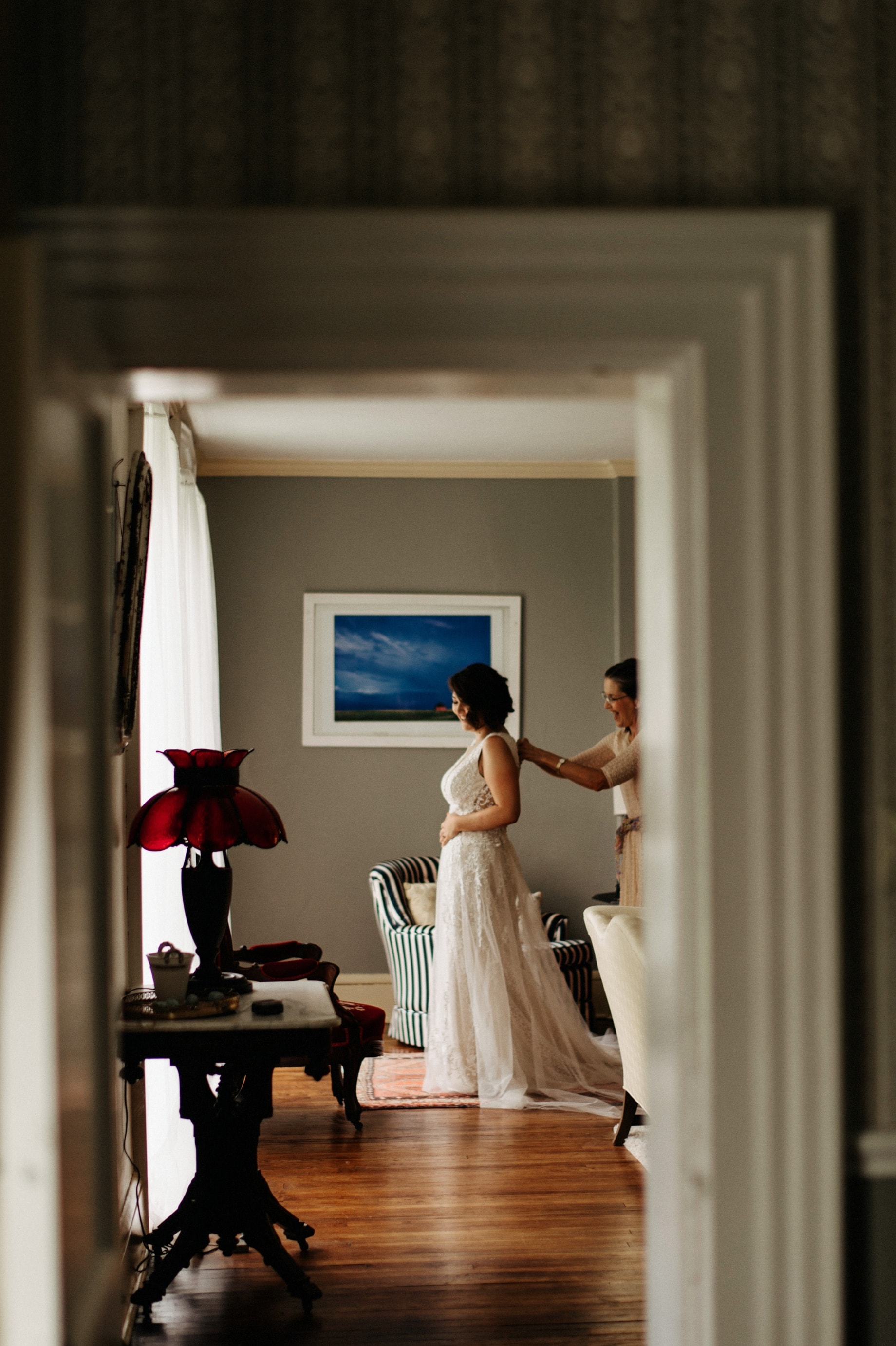 bride being helped into dress at front room of orchard house bed and breakfast