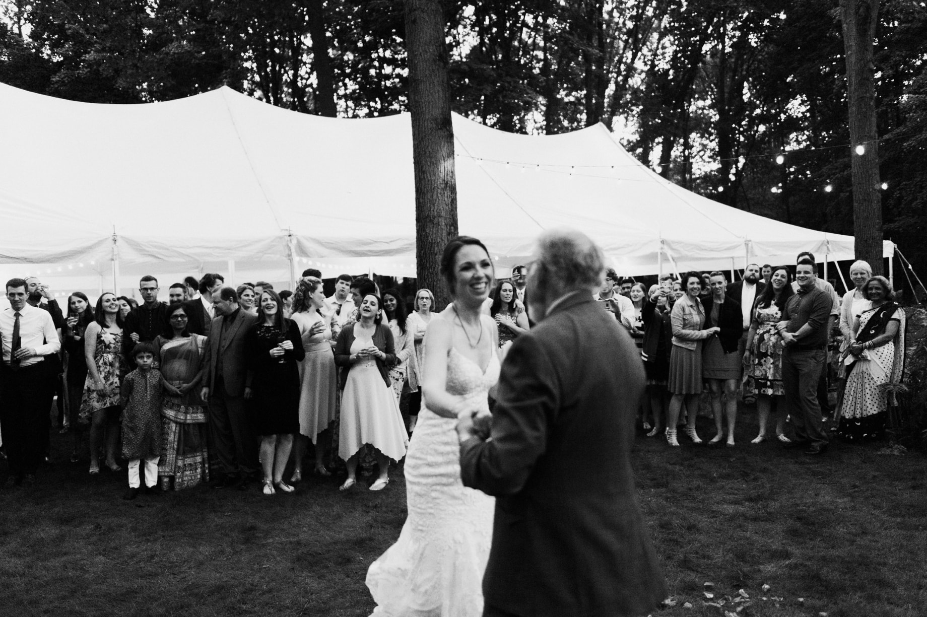 bride dancing with her father as wedding guests look on