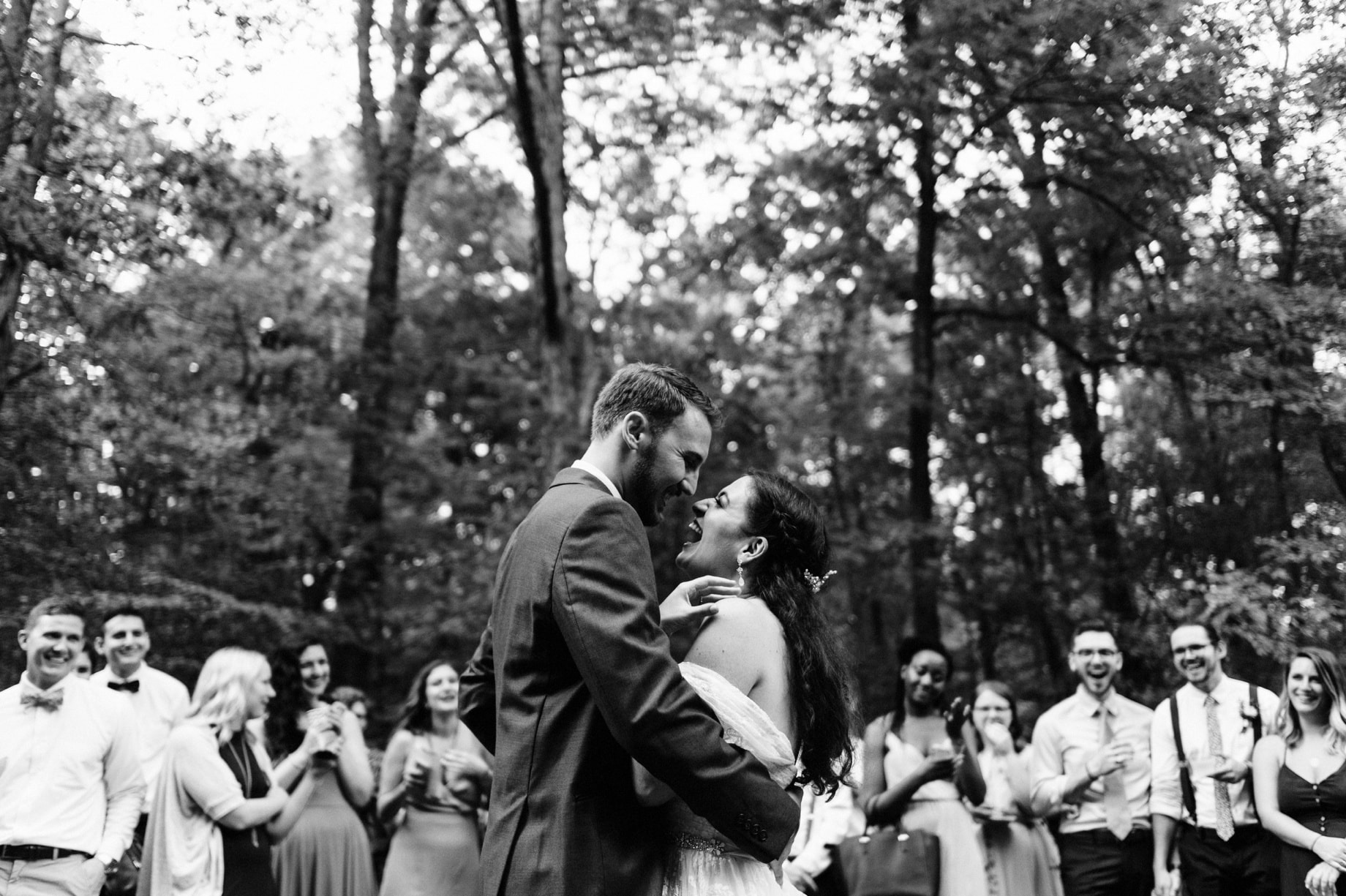 bride and groom dancing as their guests look on during their forest camp wedding