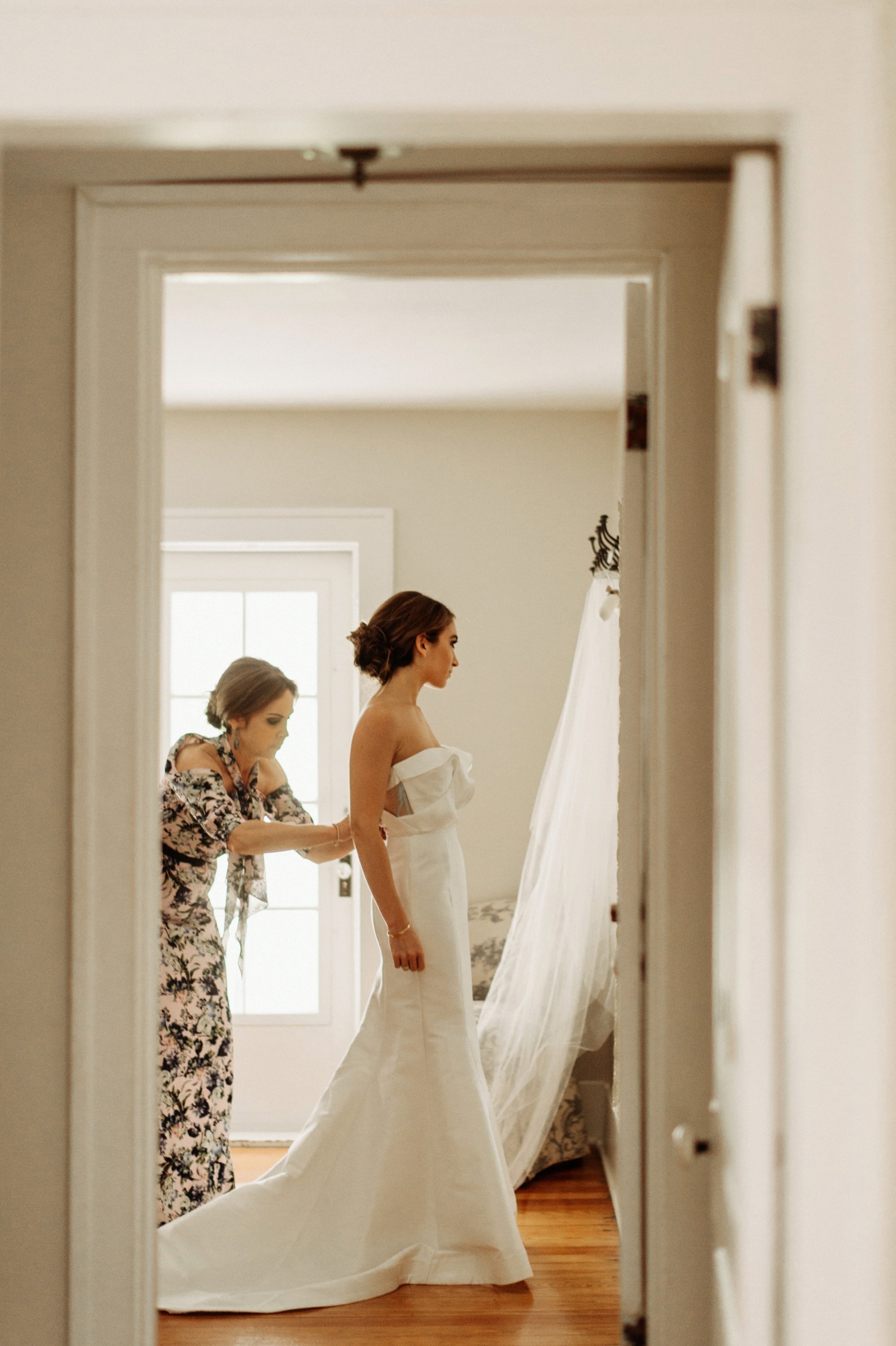 mother helps bride into her dress by Detroit wedding photographer Heather Jowett