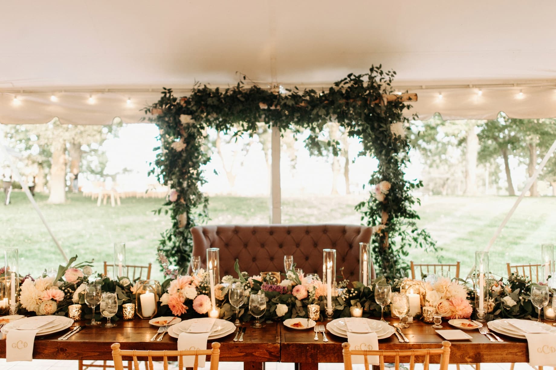 head table with lots of greenery and florals at cornman farms by ann arbor wedding photographer heather jowett