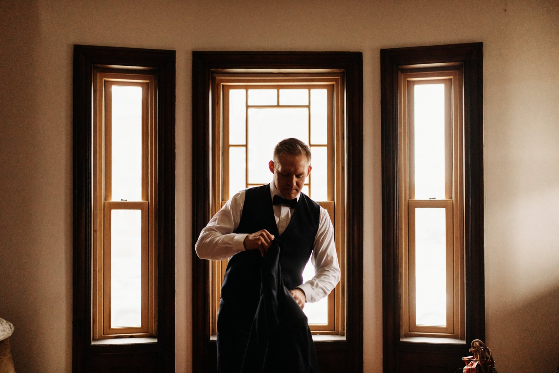 groom putting on tuxedo in Corktown Detroit by wedding photographer Heather Jowett