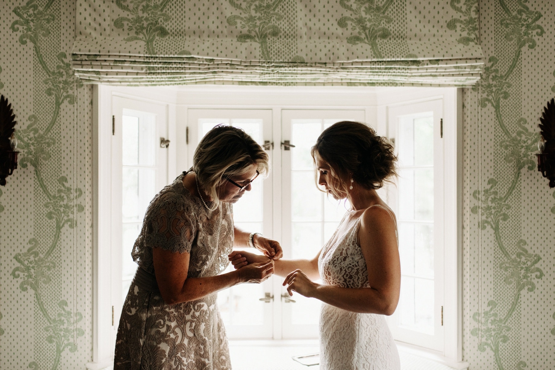 mother of the bride helps her daughter put on a bracelet