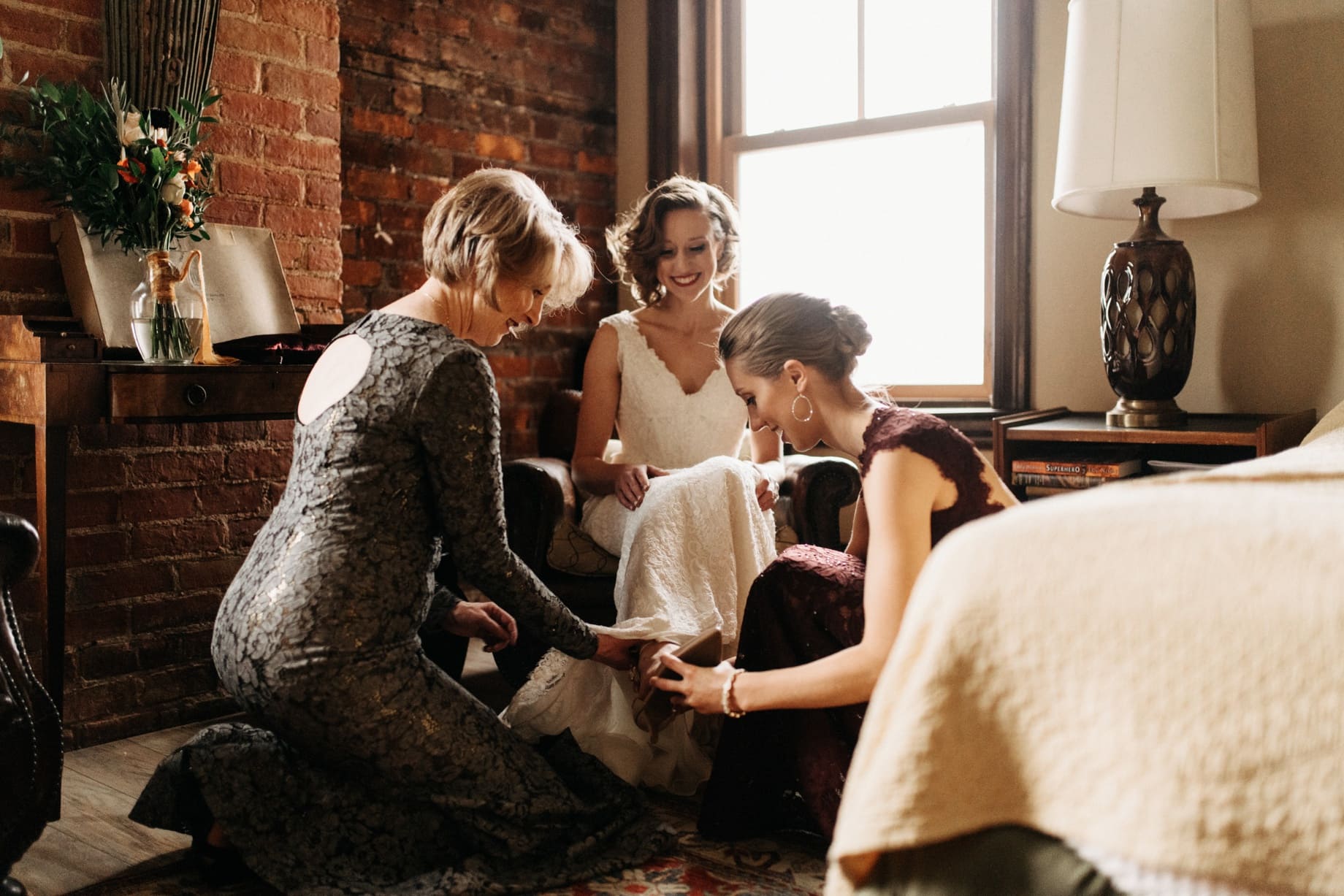 bride helped into her shoes by her sister and her mother