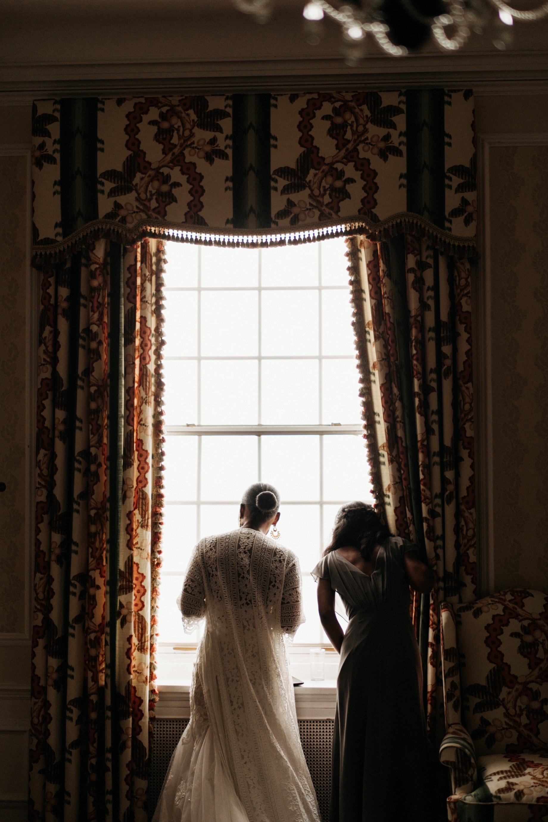 bride looking out the window at the Gross pointe war Memorial before her wedding ceremony