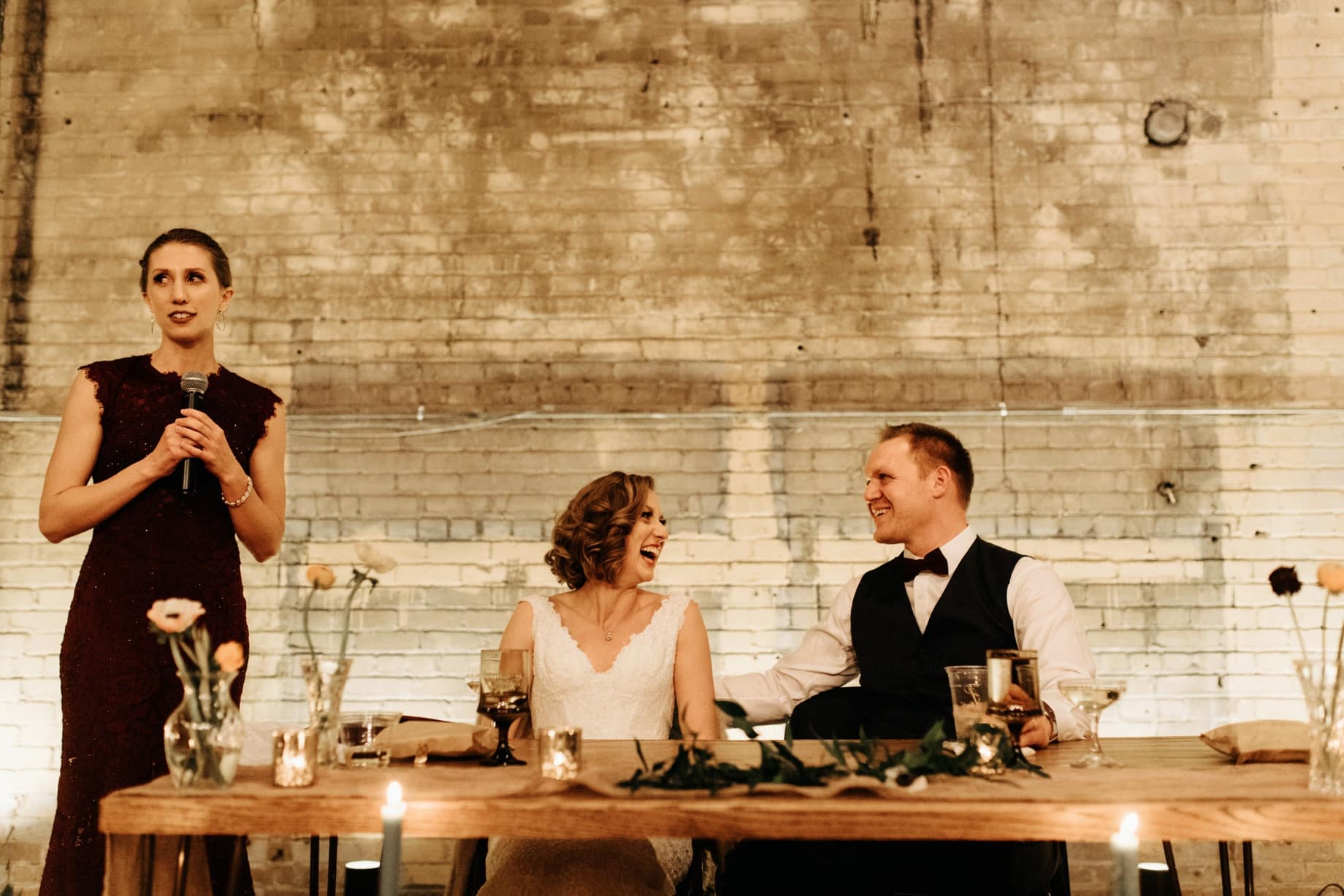 bride and groom laughing at maid of honor speech