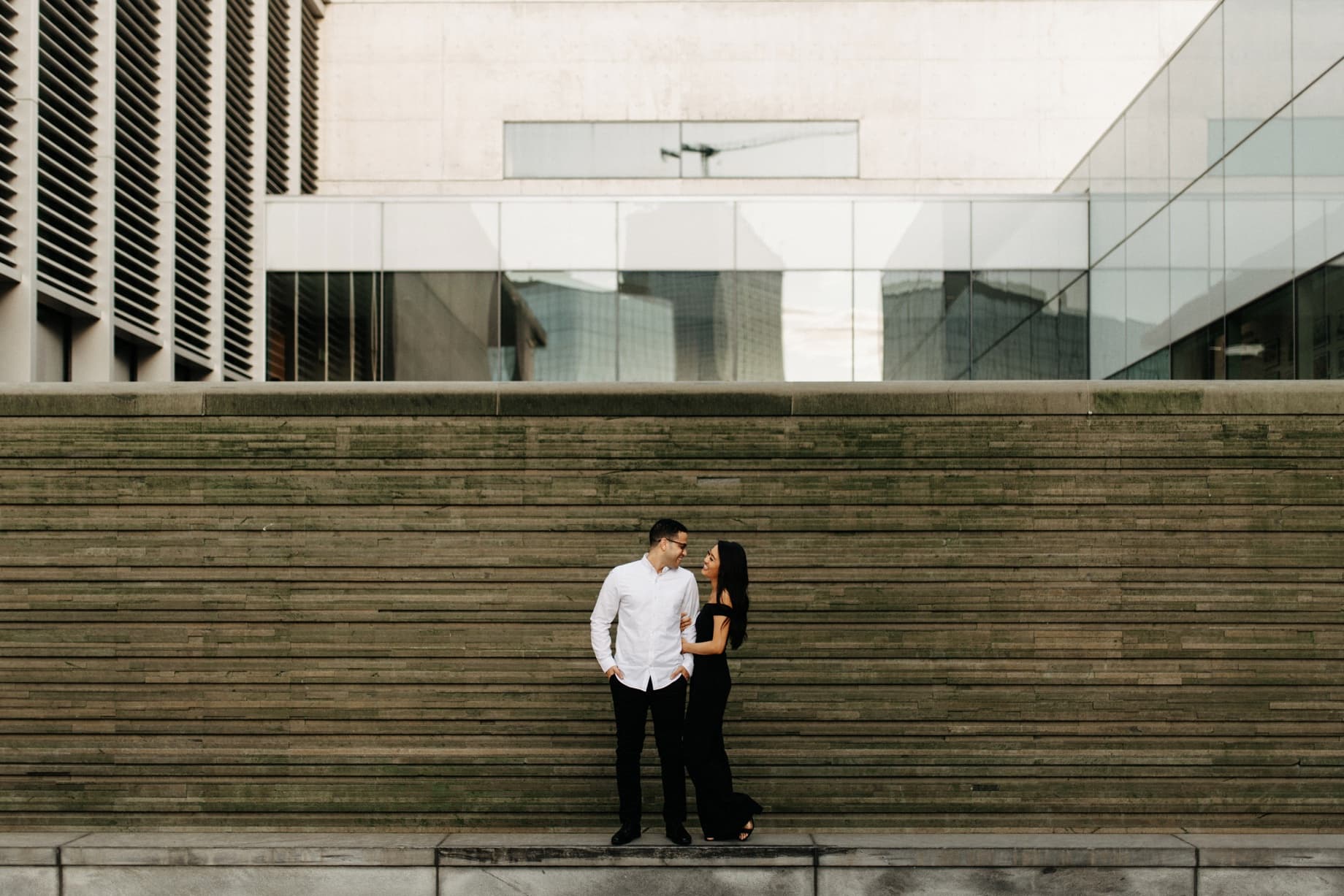 a couple poses for engagement photos at the grand rapids art museum