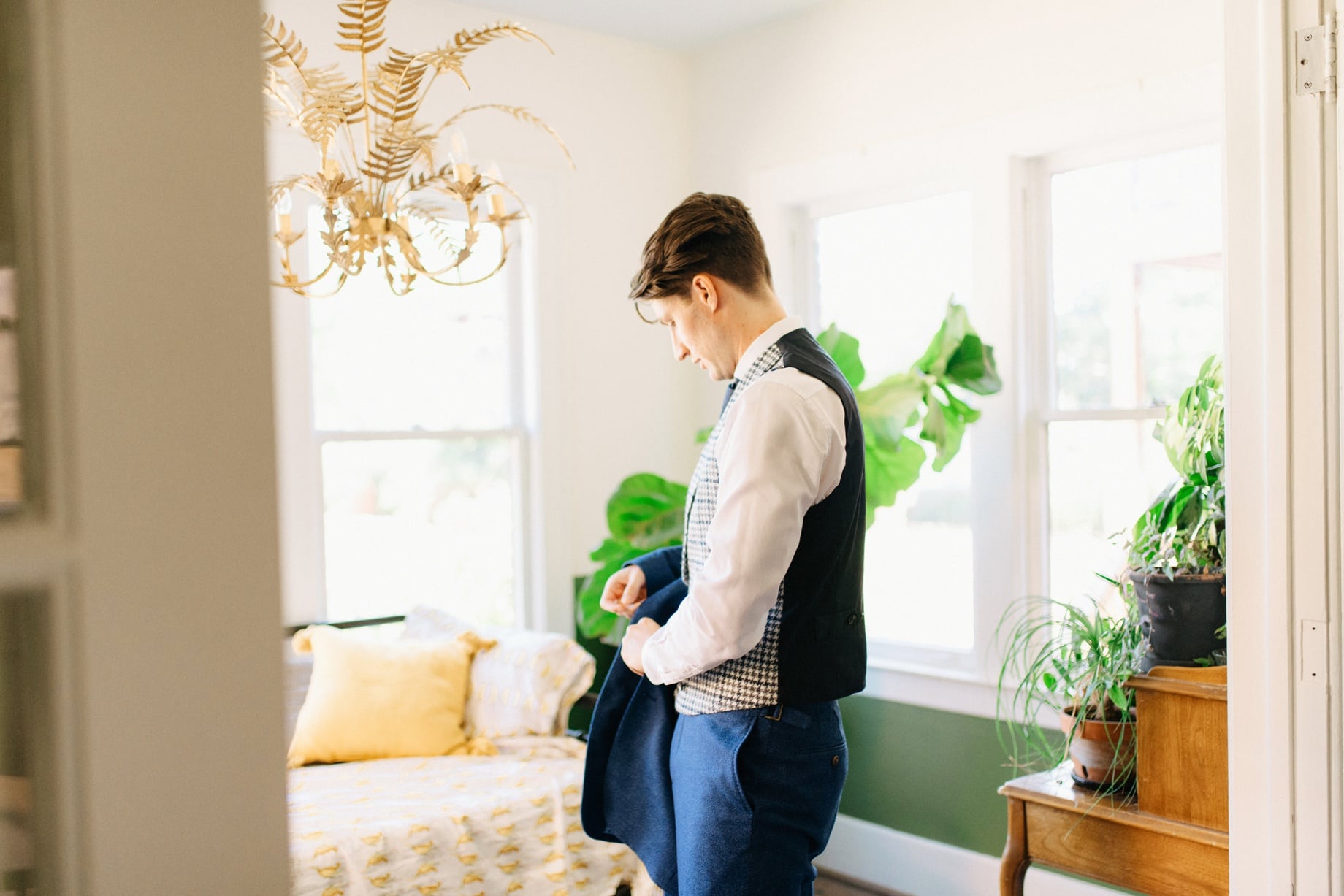 a groom puts on his jacket by photojournalistic Detroit wedding photographer Heather Jowett