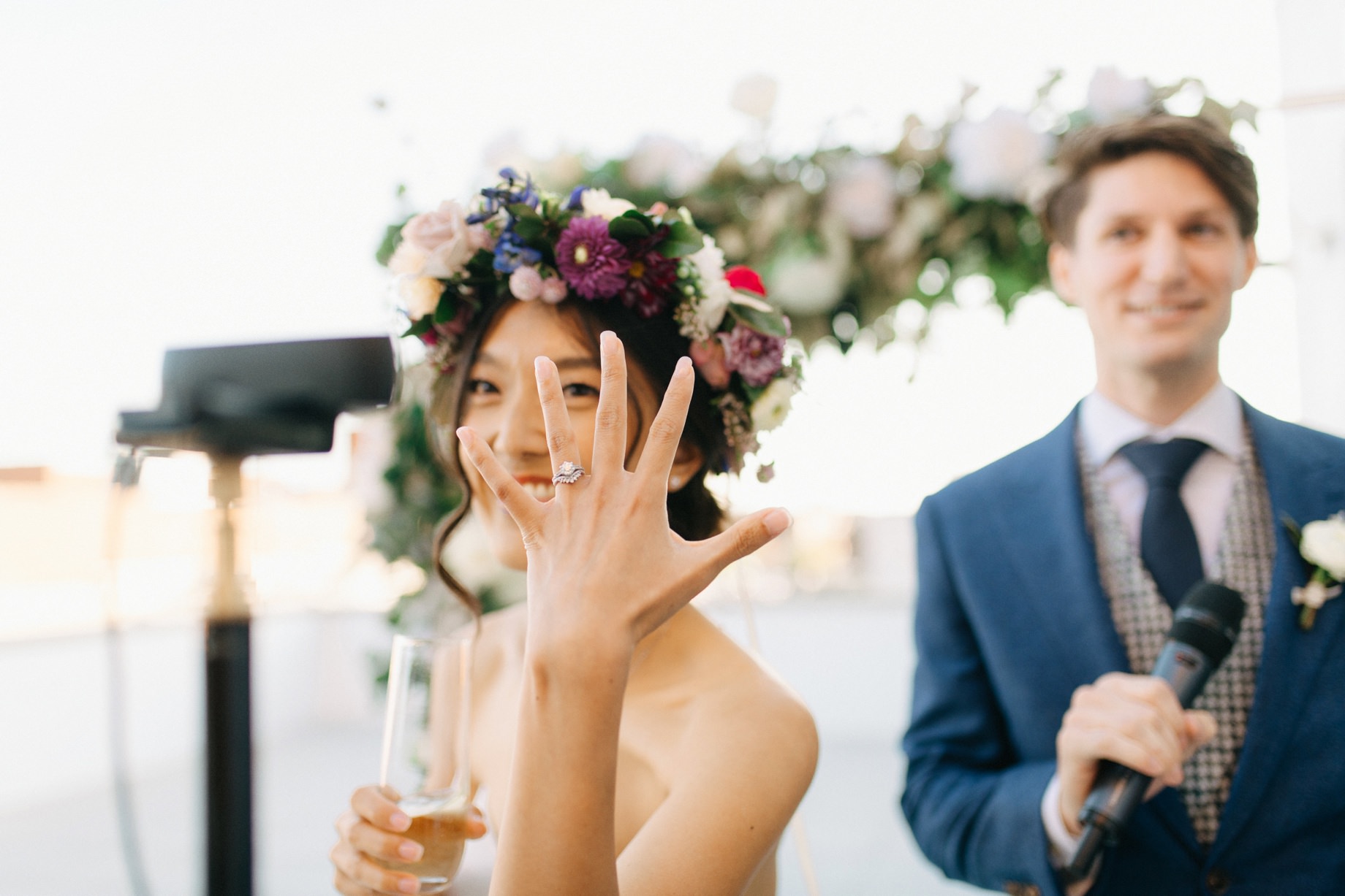 bride showing off her new ring to guests watching a live stream