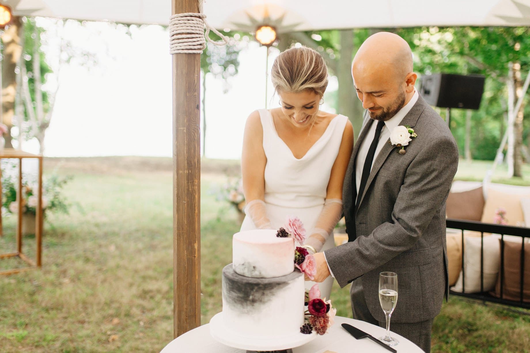 a couple cuts their wedding cake at their lakeside wedding in lexington michigan