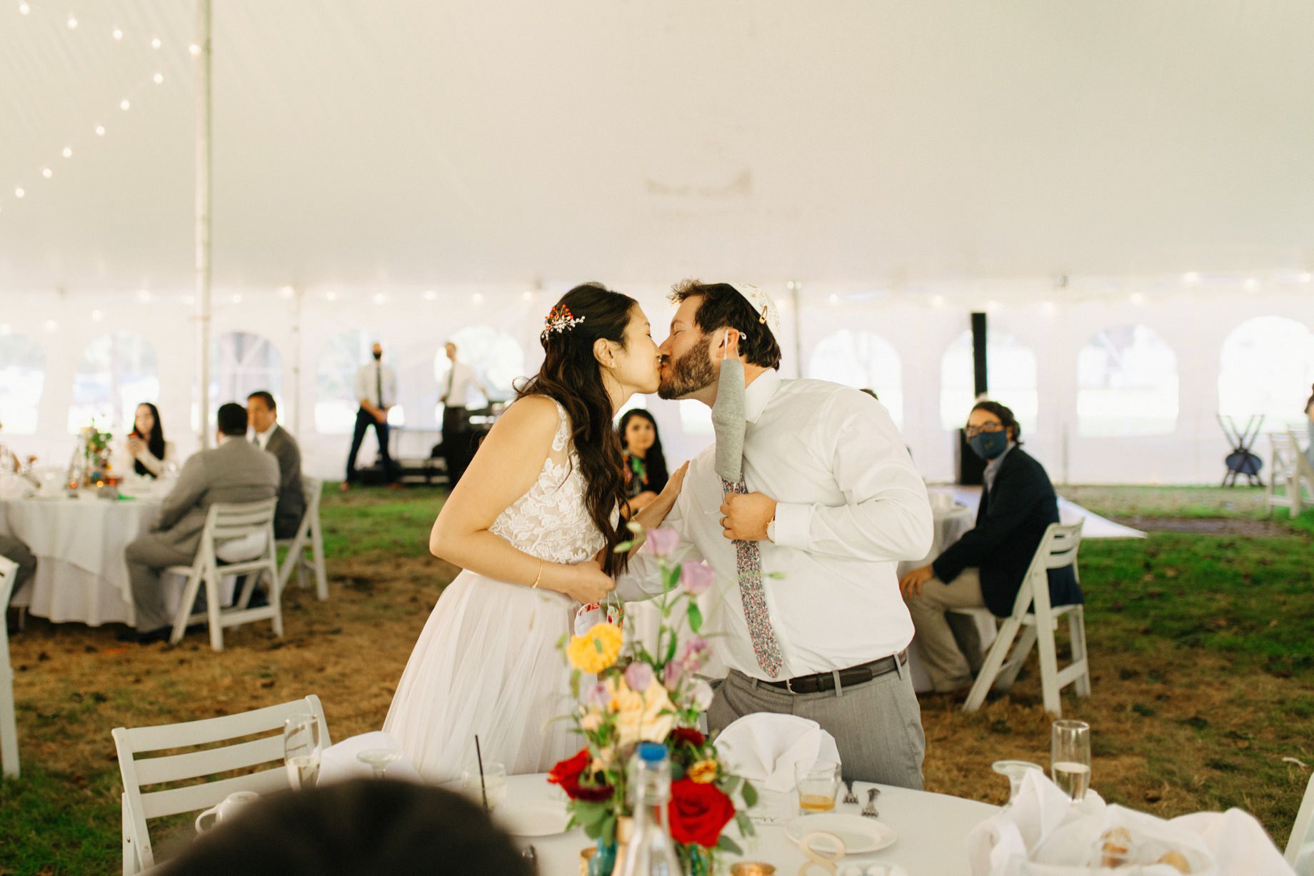 a couple shares a kiss during their wedding reception